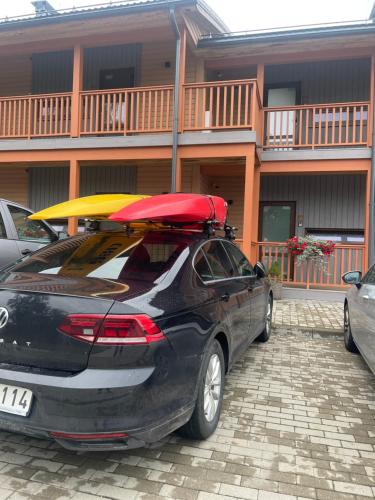 a car parked in front of a building with a surfboard on the roof at Bestes apartamenti in Kocēni