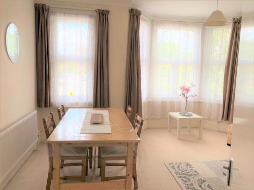 a dining room with a table and chairs and windows at Spacious West London 2 Bedroom Apartment in London