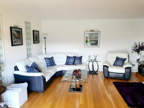 a living room with a white couch and two chairs at Lindas Retreats Self catering accommodation 1 bedroom cottage or 3 bedroom House in Tomintoul