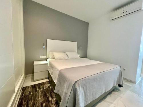 um quarto com uma cama com uma colcha branca em Apartamento La Victoria em Córdoba