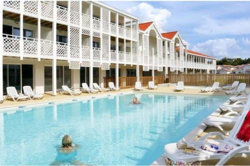 - une piscine dans un hôtel avec des chaises et des personnes dans l'établissement COTE SOLEIL, à Mimizan