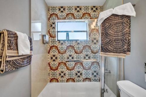 uma casa de banho com um chuveiro, um WC e uma janela. em Luxury 3bd/2ba near Beach & Las Olas em Fort Lauderdale