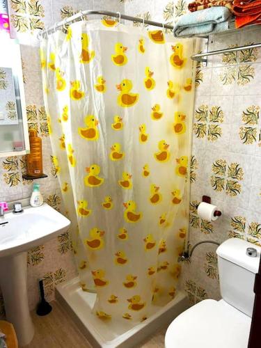 uma casa de banho com uma cortina de chuveiro com patos em Cómodo alojamiento muy cerca de la playa em El Perellonet