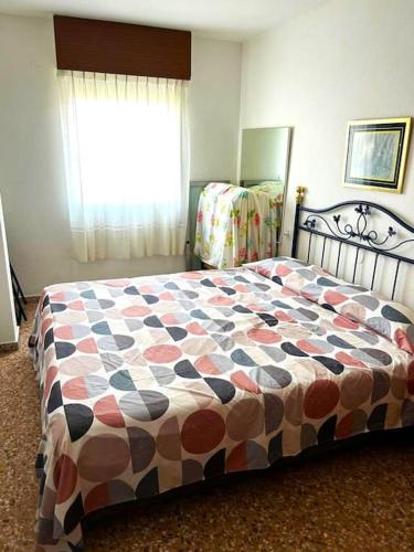 um quarto com uma cama com um edredão colorido em Cómodo alojamiento muy cerca de la playa em El Perellonet