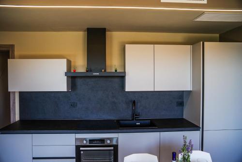 a kitchen with white cabinets and a sink at Vista Langhe - CerratoHouses in Guarene