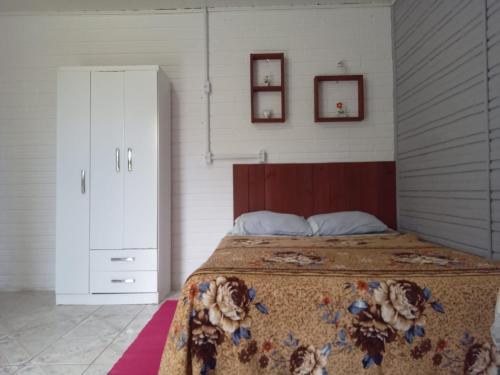 Hospedaria Mirante da Maré ap8 في إيمبيتوبا: غرفة نوم بسرير وكابينة وصورتين على الحائط