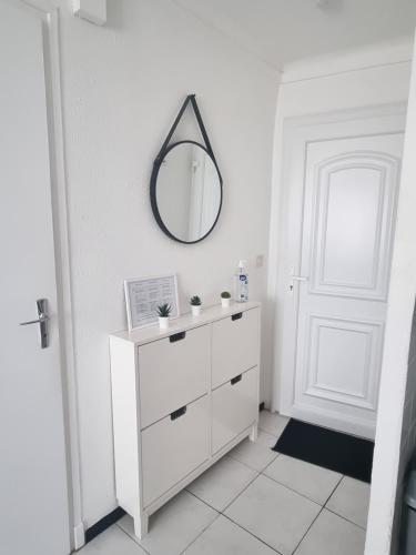- une salle de bains blanche avec un miroir et une commode blanche dans l'établissement Appartement coquet Le Boulou, au Boulou