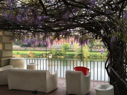 フィレンツェにあるLungarno Ponte Vecchioの白い椅子と紫の花の大きな窓が備わる客室です。