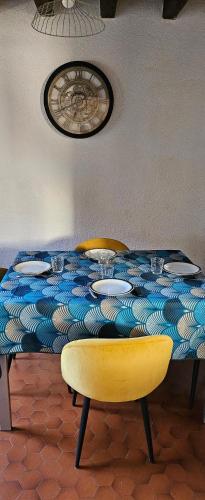 uma mesa com uma cadeira amarela e uma toalha de mesa azul e branca em Au Bois Fleuri em Bracieux