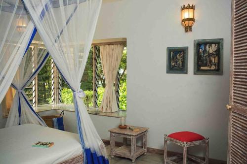 1 dormitorio con cama con dosel y ventana en Dolphin House, Galu Beach, Kenya, en Ukunda