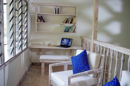 Cette chambre comprend un bureau avec un ordinateur portable installé sur une chaise. dans l'établissement Dolphin House, Galu Beach, Kenya, à Ukunda