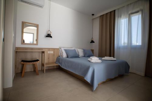 ein Schlafzimmer mit einem blauen Bett und einem Spiegel in der Unterkunft Kotinos Luxury Suites in Skyros