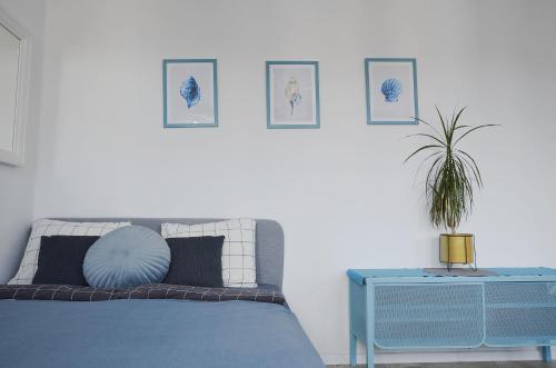 a bedroom with a bed with a blue table and pictures on the wall at Apartament Targ Stare Miasto z widokiem! in Gdańsk