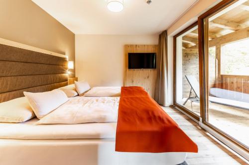 a bedroom with a bed and a large window at Das Bayrischzell Familotel Oberbayern in Bayrischzell
