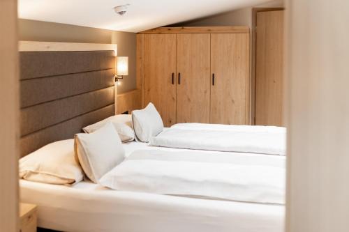 two white beds in a room with wooden cabinets at Das Bayrischzell Familotel Oberbayern in Bayrischzell