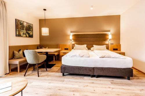 a hotel room with a bed and a dining room at Das Bayrischzell Familotel Oberbayern in Bayrischzell