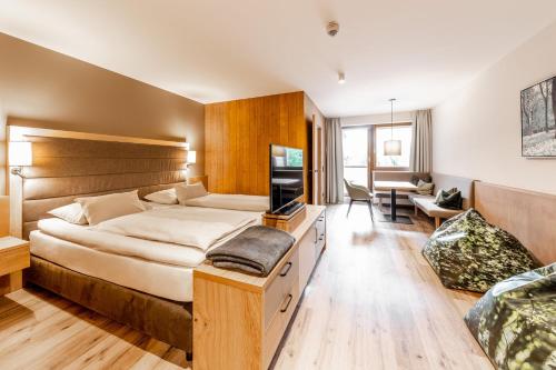 a bedroom with a large bed and a living room at Das Bayrischzell Familotel Oberbayern in Bayrischzell