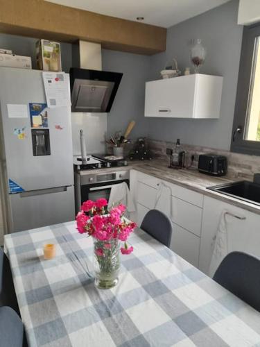 une cuisine avec une table avec un vase de fleurs dessus dans l'établissement Maison calme proche centre ville, à Coulaines