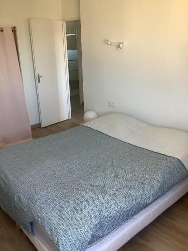 une chambre avec un lit avec une couverture bleue dans l'établissement Maison entre mer et garrigue, à Balaruc-les-Bains