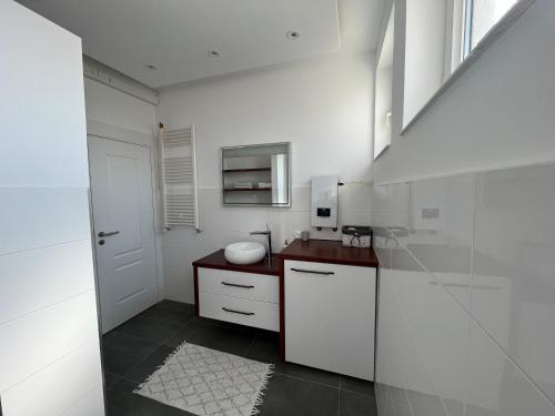 a white kitchen with a sink and a microwave at Qendresa Apartments in Prishtinë
