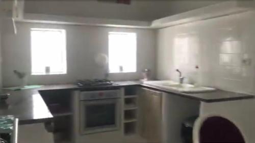 a kitchen with a stove and a sink and two windows at Dar Blanche in Hammamet