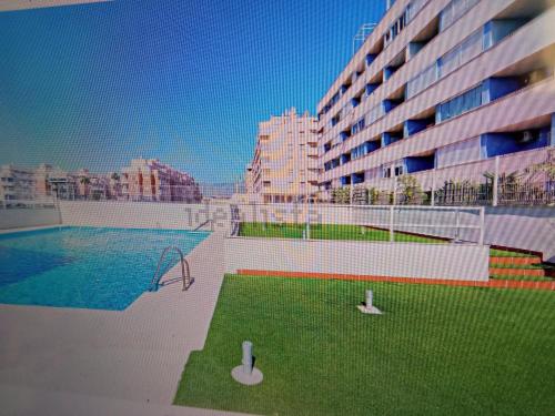 un grand immeuble avec piscine et pelouse dans l'établissement Sela Playa, à Roquetas de Mar