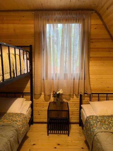 1 dormitorio con 2 camas individuales y ventana en Agaruka Cabin Racha, en Ambrolauri