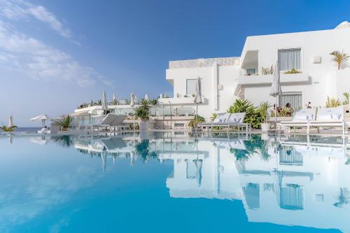 a swimming pool in front of a white building at Lani's Suites de Luxe - Adults Only in Puerto del Carmen