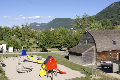 an outdoor playground with a building and a slide at Village de Gites le Colombier in Mende