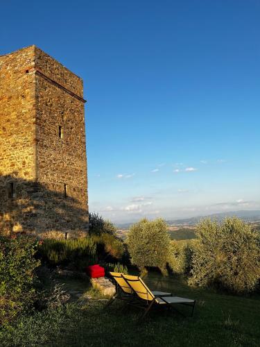 a table and two chairs sitting next to a building at Medieval Tower in Umbria with Swimming Pool in Monte lʼAgello