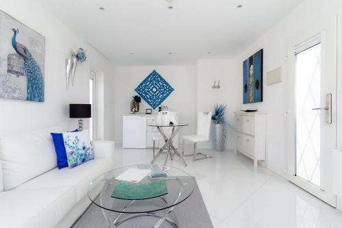 a white living room with a white couch and a glass table at Lani's Suites de Luxe - Adults Only in Puerto del Carmen