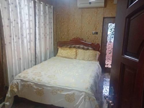 um quarto com uma cama com lençóis brancos e uma janela em Victorus Homes em Freetown