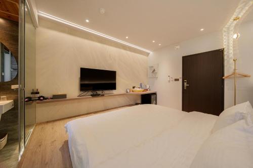 a bedroom with a large bed and a flat screen tv at Tin Gan Beauty Hotspring in Yuanshan