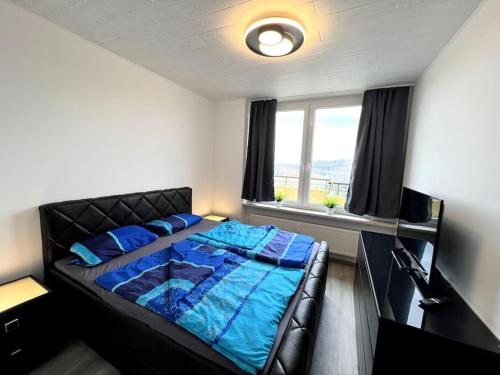 a bedroom with a bed with blue sheets and a window at Penthouse Brockenblick 381 in Braunlage