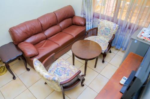 a living room with a couch and chairs and a table at Shangri-la Hotel Muyenga in Bugolobi