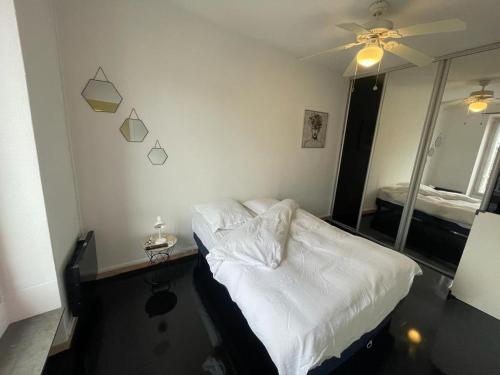 een slaapkamer met een wit bed en een spiegel bij Valérie in Étampes