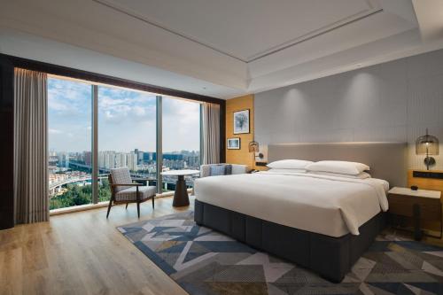 a bedroom with a large bed and a large window at Sheraton Shanghai Pudong Riverside in Shanghai