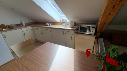 an attic kitchen with a table and a microwave at Rooms 4 Holiday in Kirchbach
