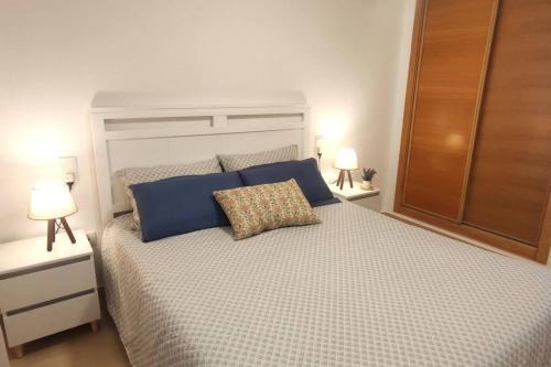 um quarto com uma cama com almofadas azuis e 2 candeeiros em Condado de Alhama Beautiful New Apartment with Golf Course Views em Alhama de Múrcia