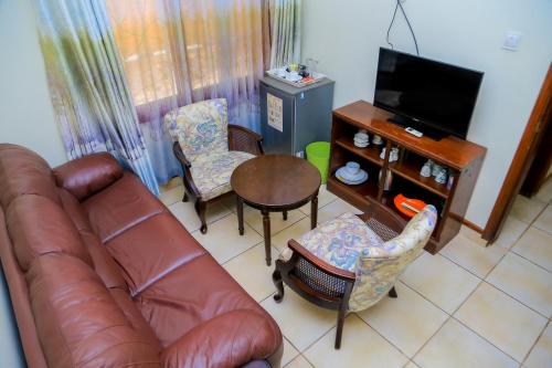 a living room with a leather couch and chairs and a table at Shangri-la Hotel Muyenga in Bugolobi