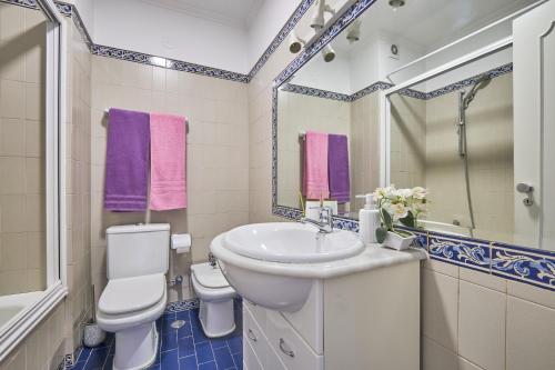 a bathroom with a sink and a toilet and a mirror at Aiyra Beach House in Costa da Caparica