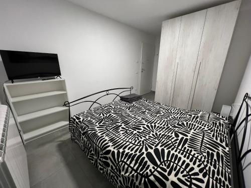 a bedroom with a black and white bed and a tv at San Rocco 30 - camera in campagna - Piombino in Piombino