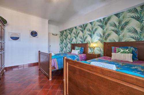 a bedroom with two beds and a mural of palm trees at Aiyra Beach House in Costa da Caparica