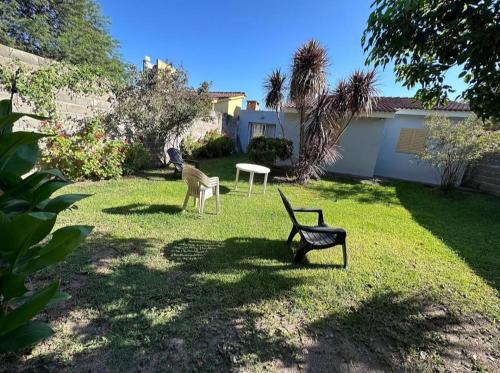 einen Hof mit zwei Stühlen und einer Bank im Gras in der Unterkunft Cabaña El Silencio in Los Algarrobos