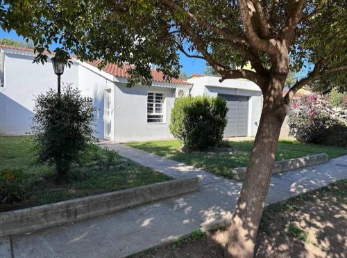 ein weißes Haus mit einem Baum und einem Gehweg in der Unterkunft Cabaña El Silencio in Los Algarrobos