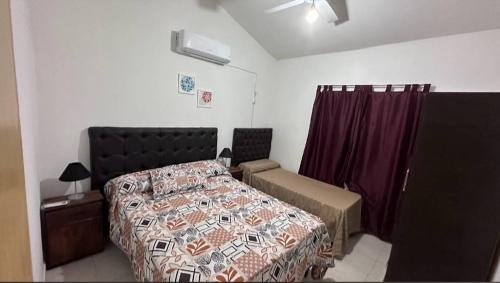 ein Schlafzimmer mit einem Bett, einem Stuhl und Vorhängen in der Unterkunft Cabaña El Silencio in Los Algarrobos