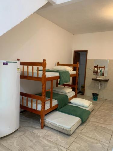 four bunk beds in a room with a refrigerator at Planeta Verde Apartamentos in Itacaré