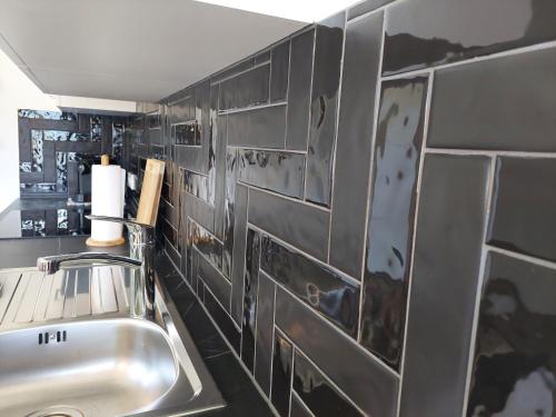 a kitchen with a sink and a tiled wall at Dolomitenhome Apartments in Patriasdorf