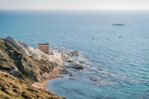a building on a cliff next to the ocean at Emesh Boutique Suite in Agrigento