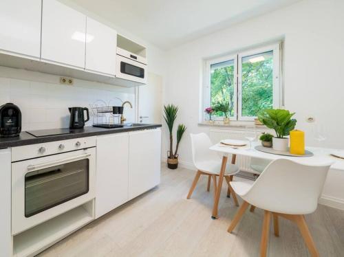 a white kitchen with a table and white chairs at 1OG Mitte Wunderschöne 68m² große 2-Zimmer City Wohnung nähe Salzburg in Freilassing